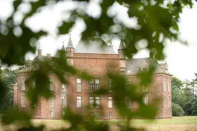 a large red brick castle with trees in the foreground at B&B Carpe Diem in Westerlo