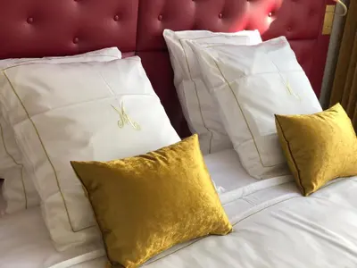 a bed with white pillows and gold pillows at Merveilleux in Ghent