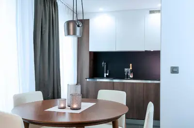 a kitchen and dining room with a wooden table and white chairs at Aparthotel Residence Agenda in Brussels