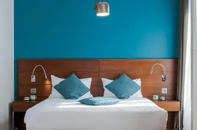 a bedroom with a blue wall and a bed with blue pillows at Aparthotel Residence Agenda in Brussels