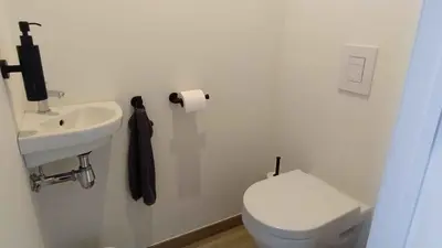 a white bathroom with a toilet and a sink at B&B Plattestien in Halle