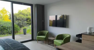a bedroom with green chairs and a large window at B&B Plattestien in Halle