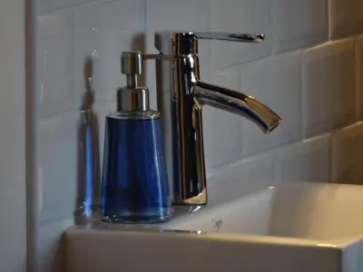 a sink with a faucet and a blue soap dispenser at B&B Welcome To My Place in Brussels