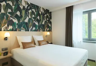 a bedroom with a large white bed and a large window at Le Côté Vert in Waterloo