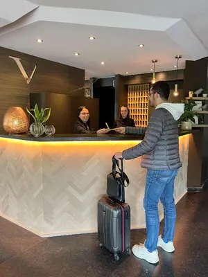 a man standing at a bar with a suitcase at Le Côté Vert in Waterloo