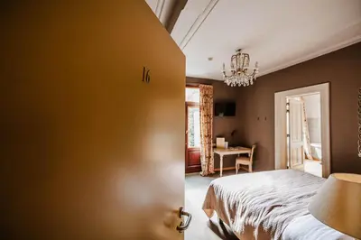 a bedroom with a bed and a table in a room at Boutique hotel Roosendaelhof in Geel