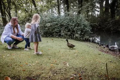 a woman and two children looking at a duck at Boutique hotel Roosendaelhof in Geel