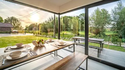 a dining room with large windows and a view of a garden at VELPE 55 in Bierbeek