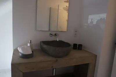 a bathroom with a stone sink and a mirror at ma-tinée in Beauvechain