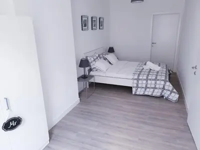 a white bedroom with a bed and a lamp at Brussels appartments luxury in Brussels