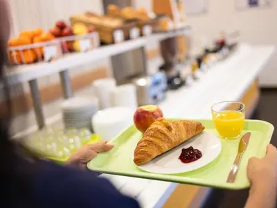 a person holding a tray with a plate of food at ibis Budget Brussels South Ruisbroek in Ruisbroek