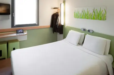 a bedroom with a large bed with white pillows at ibis Budget Brussels South Ruisbroek in Ruisbroek