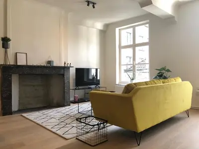 a living room with a yellow couch and a fireplace at Bed & Boon in Ghent
