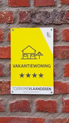 a yellow sign on the side of a brick wall at Vakantiewoning De Schuur Tienen in Tienen