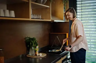 a woman standing in a kitchen preparing food at MEININGER Hotel Bruxelles Gare du Midi in Brussels