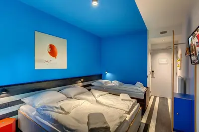 two beds in a room with a blue wall at MEININGER Hotel Bruxelles Gare du Midi in Brussels