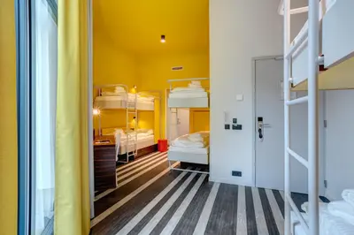 a dorm room with bunk beds and a yellow ceiling at MEININGER Hotel Bruxelles Gare du Midi in Brussels