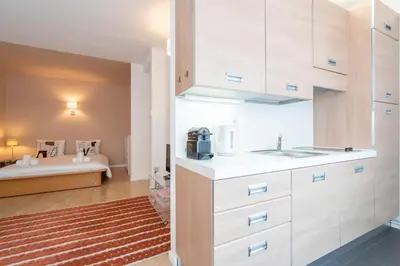 a kitchen with white cabinets and a bed in the background at Theaterstudio 1 Antwerp in Antwerp