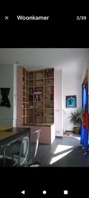 a dining room with a table and a book shelf at Land Scape guesthouse in Eeklo