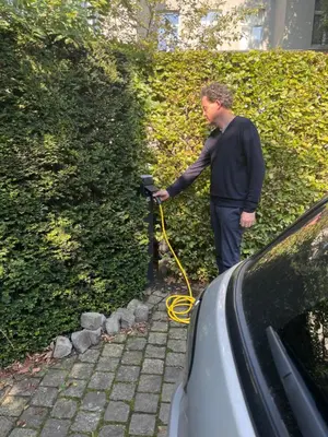 a man with a yellow hose connected to a hedge at Holiday Home Jules in Antwerp