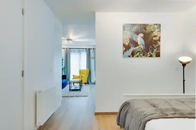 a white bedroom with a bed and a yellow chair at Royal Arts-Loi Studio in Brussels
