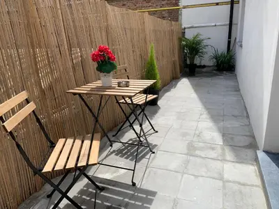 a patio with a table and two chairs and a vase of flowers at Attractive modern apartment in Brussels