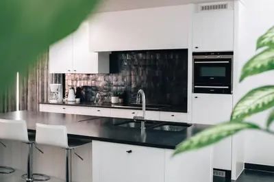 a kitchen with white cabinets and a black counter top at Gadering in Zele