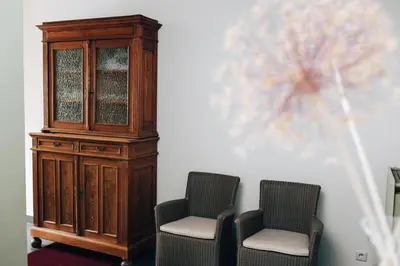 two chairs and a wooden cabinet next to a wall at Gadering in Zele