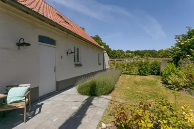 a white house with a bench and a yard at Scheldewegel Vakantiehuis in Schelderode