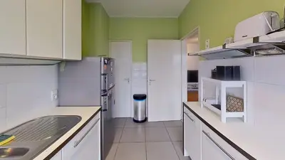 a kitchen with white cabinets and green walls at nice and cosy apartment in Edegem