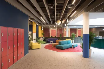 an office lobby with red lockers and couches at ROXI The Urban Residence Brussels in Brussels