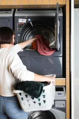 a woman is putting food into an oven at ROXI The Urban Residence Brussels in Brussels
