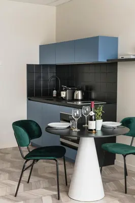 a kitchen with green chairs and a table with wine glasses at ROXI The Urban Residence Brussels in Brussels