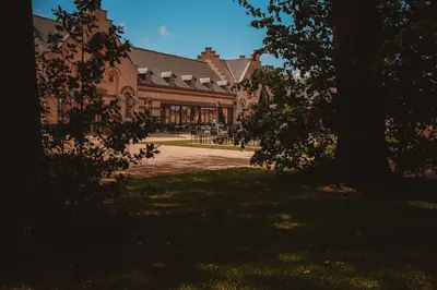 a large building with a tree in front of it at Hotel Colonie 7 in Merksplas