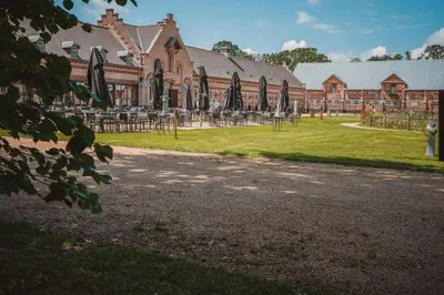 a building with a yard with tables and umbrellas at Hotel Colonie 7 in Merksplas