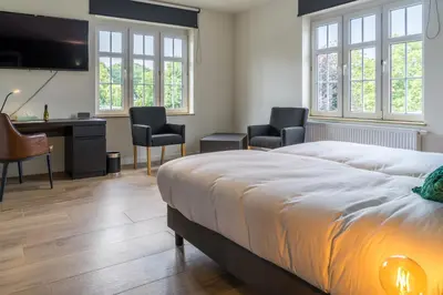 a bedroom with a bed and a desk and chairs at Hotel Huron in Mol