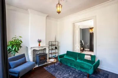a living room with a green couch and a fireplace at OsTi in Ghent