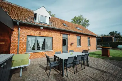 a table and chairs in front of a brick house at De Holsterhoeve in Beringen