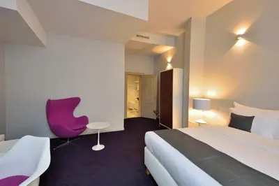 a hotel room with a bed and a purple chair at Hotel Retro in Brussels