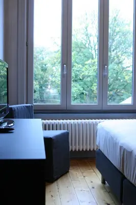 a hotel room with a bed and two windows at B&B AubergInn in Tessenderlo