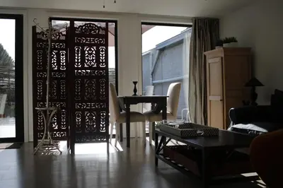 a living room with a door with a table and a piano at The Suite Escape Suite Wood in Sint-Lievens-Houtem