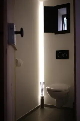 a bathroom with a toilet and a light on the wall at The Suite Escape Suite Wood in Sint-Lievens-Houtem