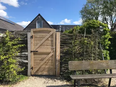 a wooden gate and a bench next to a fence at The Suite Escape Suite Wood in Sint-Lievens-Houtem