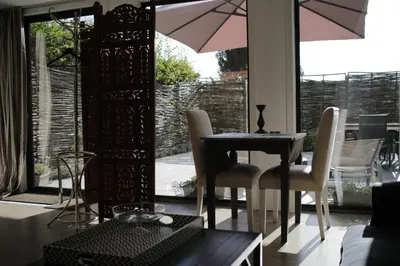 a dining room with a table and chairs and an umbrella at The Suite Escape Suite Wood in Sint-Lievens-Houtem