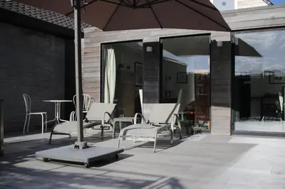 a group of chairs and an umbrella on a patio at The Suite Escape Suite Wood in Sint-Lievens-Houtem