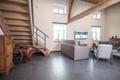 a living room with a staircase and a couch and chairs at Craywinckelhof Wagenhuis Horst in Lubbeek