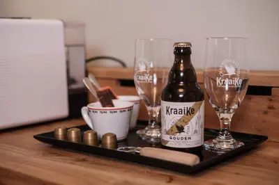 a bottle of beer and two glasses on a table at Craywinckelhof Wagenhuis Horst in Lubbeek