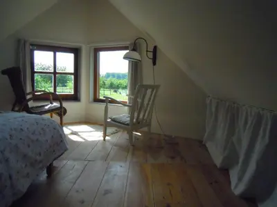 a bedroom with a bed and a chair and a window at Holiday home Brokantie in Pamel