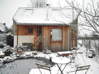 a house covered in snow with a pond in front at Holiday home Brokantie in Pamel