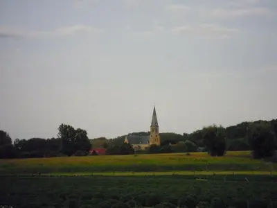 a church with a steeple in the middle of a field at Holiday home Brokantie in Pamel